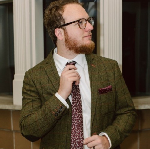 Travis Franklin looking to the side and fixing his tie